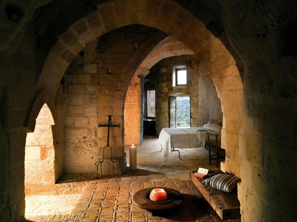 A cave room in Matera with rough stone walls, a low bed and candlelight
