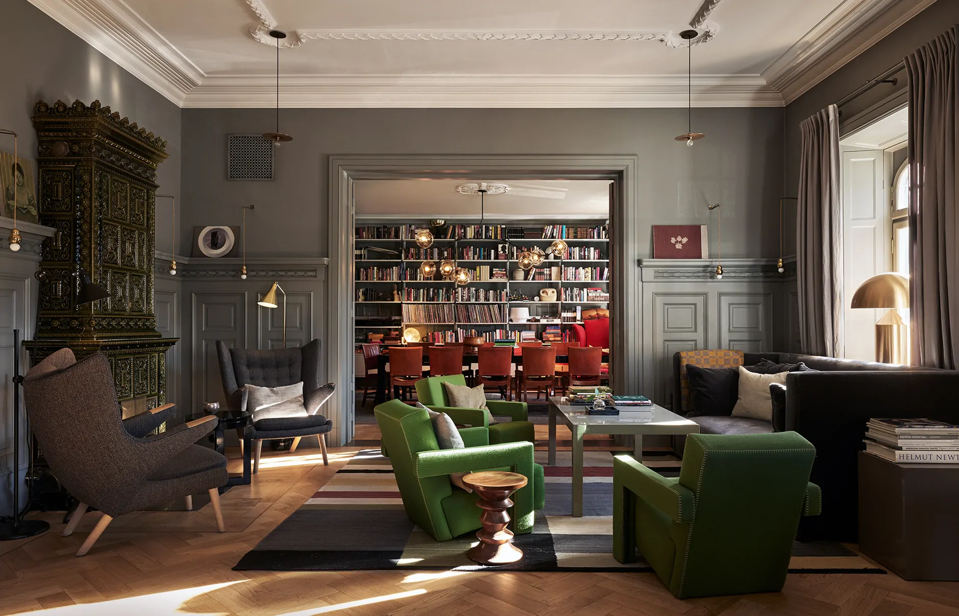 A panelled sitting room with a fireplace, armchairs and shelves of books