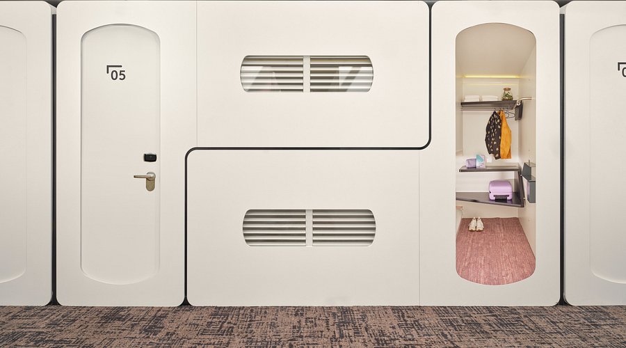 Rows of white sleeping hubs lit from within along a dark internal corridor