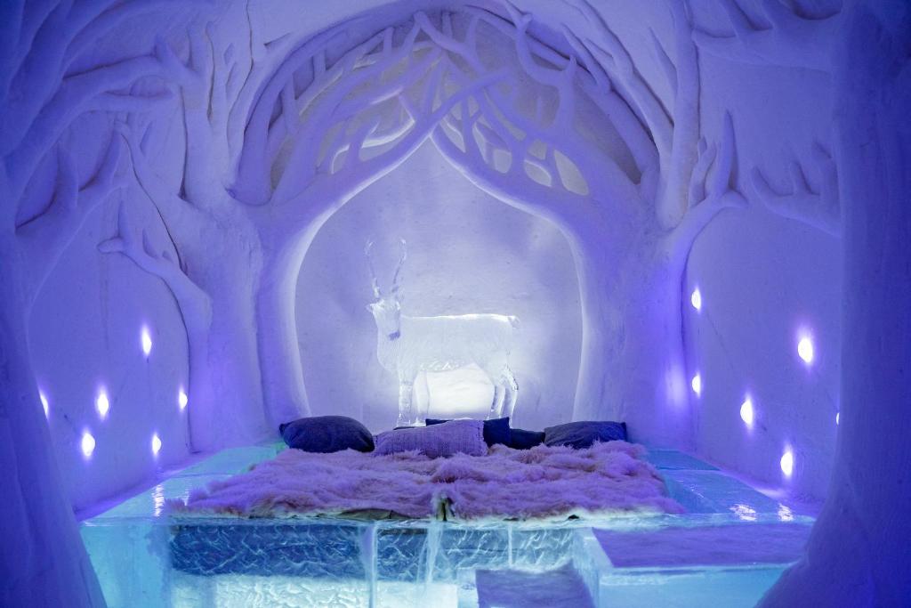 An ice bar with carved columns and glasses cut from clear ice on a snow counter