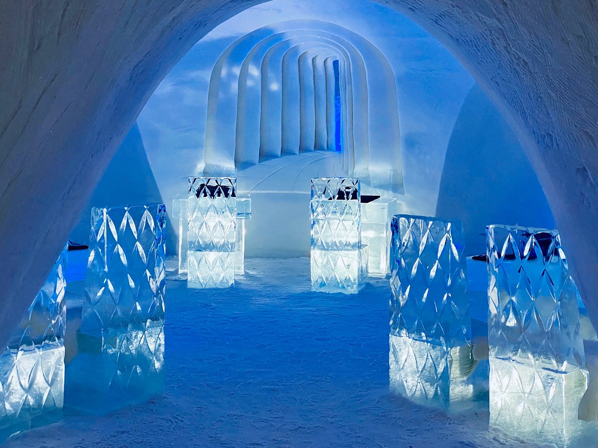 A snow chapel with carved walls and low lighting inside a built village of snow